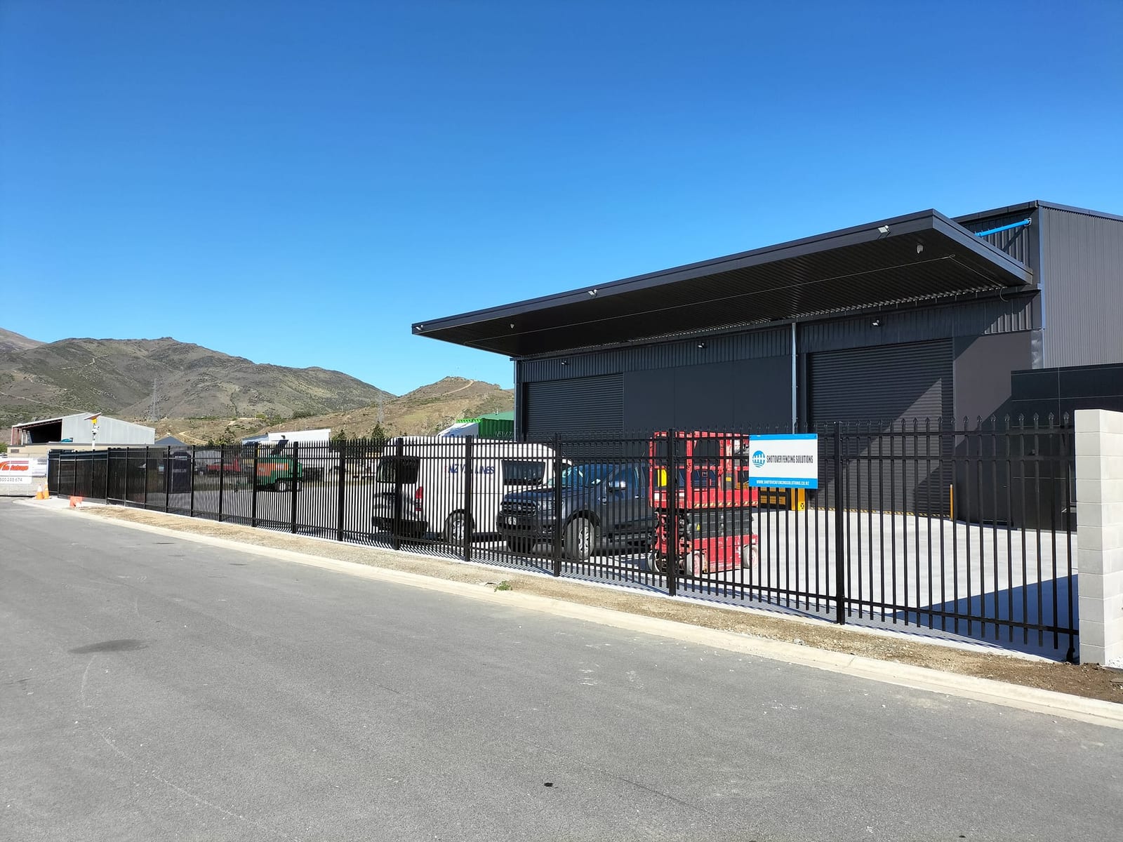 Commercial steel automatic gate with Shotover Fencing Solutions signage