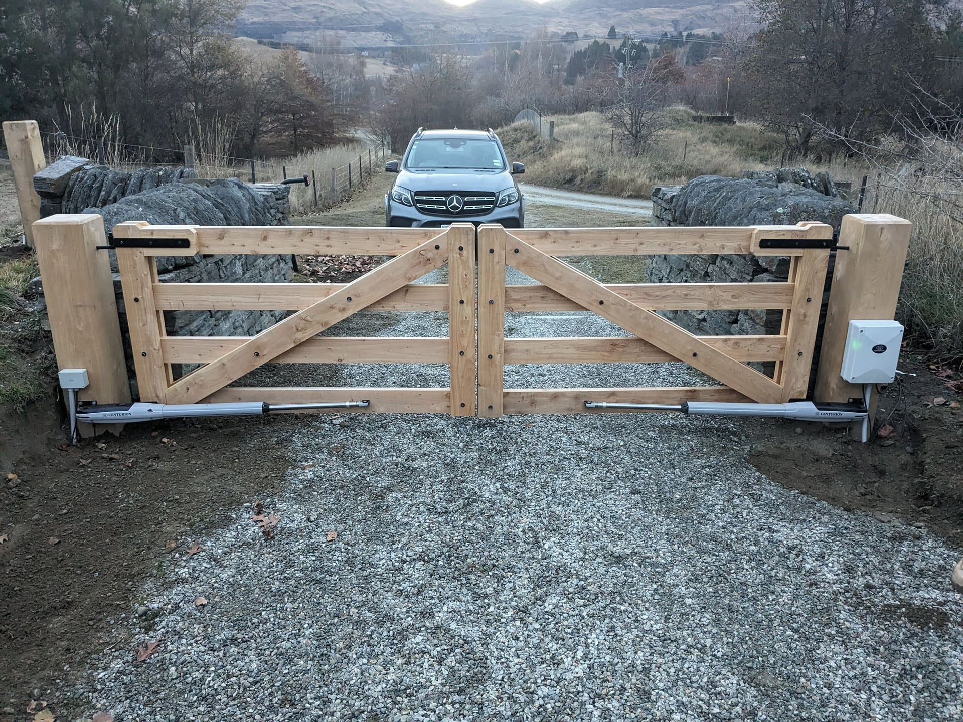 Macrocarpa double gate on a rural driveway with mountains in the background, Central Otago