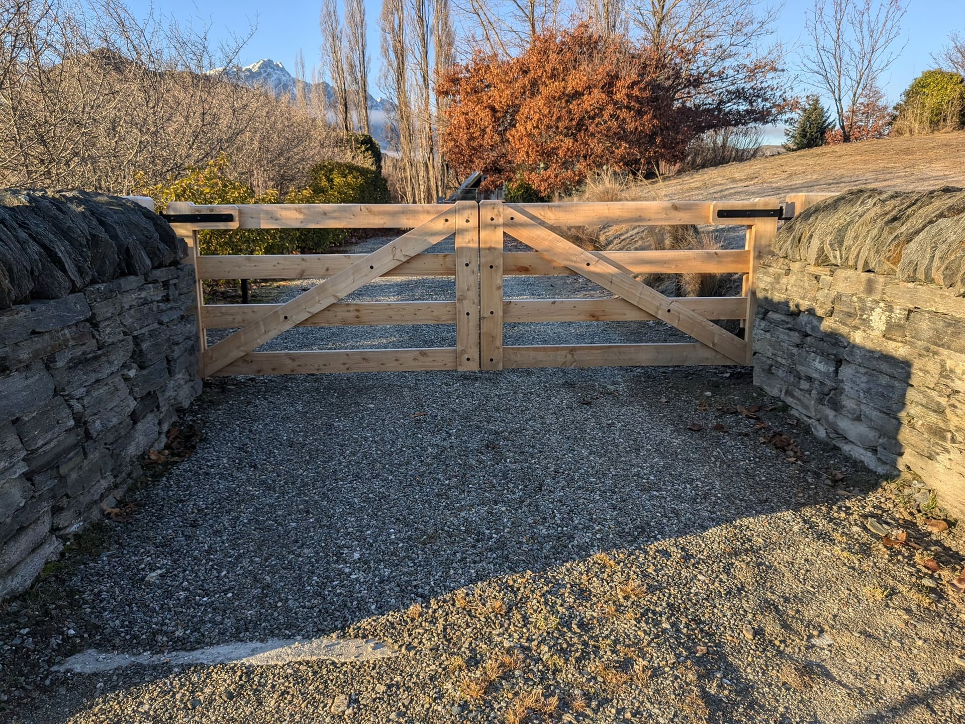Macrocarpa timber gate with schist stone walls and The Remarkables, Central Otago