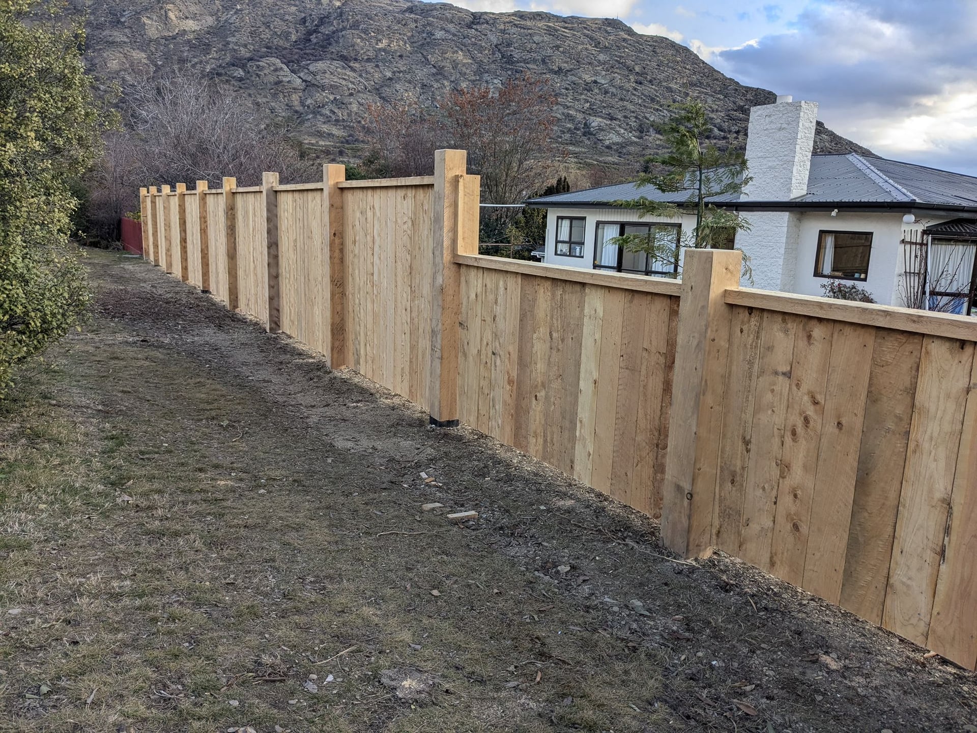 Long macrocarpa fence run with dramatic mountain backdrop, Queenstown