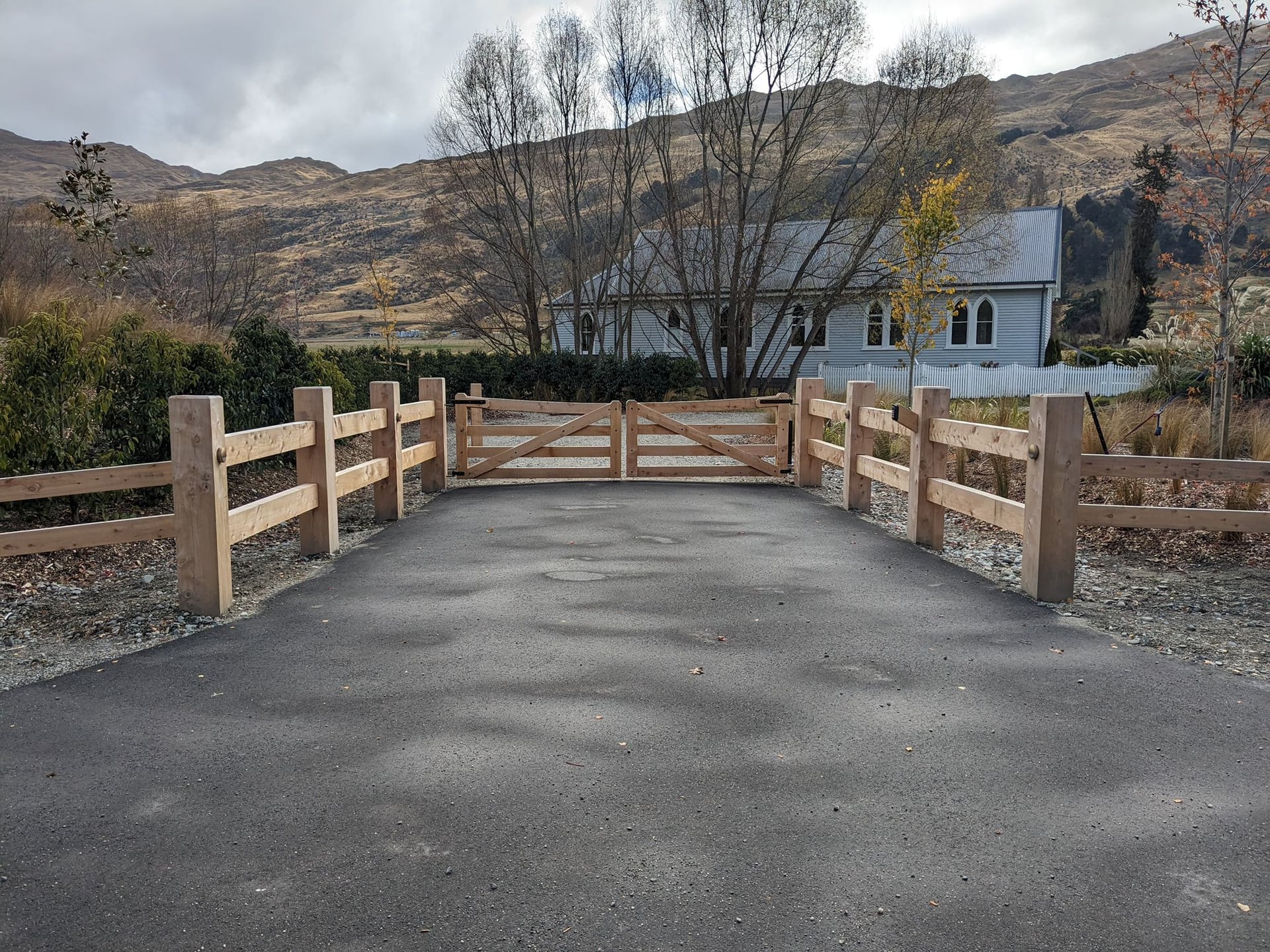Macrocarpa double gate with old church and valley views, Central Otago